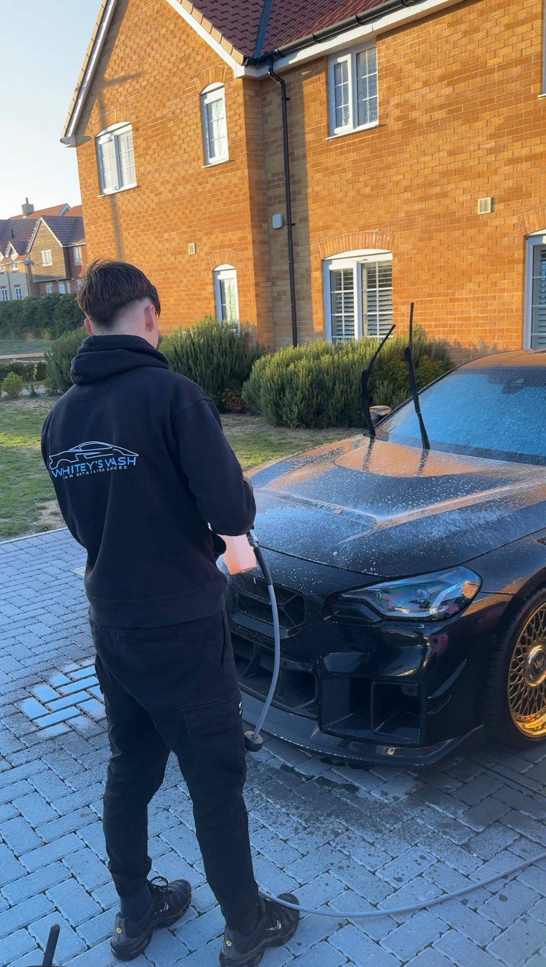 Whiteys Wash detailer foaming a black BMW M2